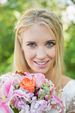 Blonde bride smiling at camera holding bouquet