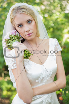 Pretty bride holding her bouquet wearing a veil