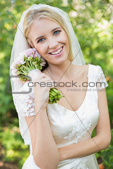 Pretty smiling bride holding her bouquet wearing a veil