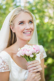 Smiling bride holding her bouquet wearing a veil looking up