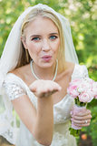 Happy bride holding her bouquet blowing a kiss