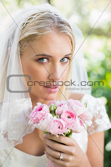Blonde bride in a veil holding her rose bouquet