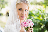 Smiling bride wearing veil holding bouquet