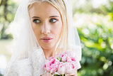 Smiling bride wearing veil holding bouquet looking over her shoulder