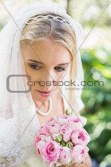 Smiling bride wearing veil holding bouquet looking down