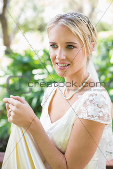 Smiling blonde bride holding her dress