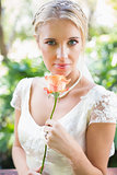 Smiling blonde bride in pearl necklace holding rose
