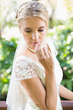 Smiling blonde bride in pearl necklace touching her lips