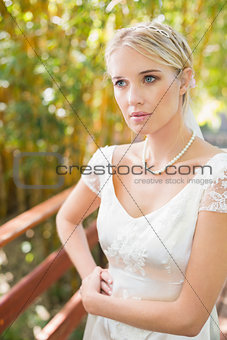 Pretty blonde bride standing on a bridge