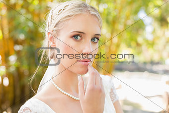 Pretty blonde bride standing on a bridge looking at camera