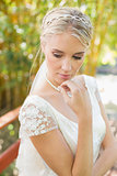 Pretty smiling blonde bride standing on a bridge looking down