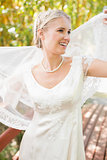 Pretty smiling blonde bride holding her veil out