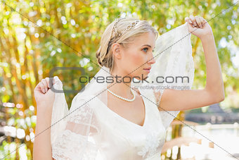 Content blonde bride holding her veil out