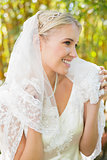Beautiful blonde bride holding her veil and smiling