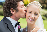 Groom kissing his pretty blonde wife on the cheek