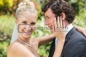 Pretty wife touching her new husbands cheek smiling at camera