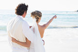 Newlyweds standing by the sea with wife pointing