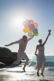 Groom holding balloons and bride holding bouquet jumping