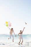 Groom holding balloons and bride throwing her bouquet jumping