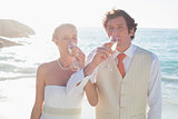 Young newlyweds drinking champagne linking arms