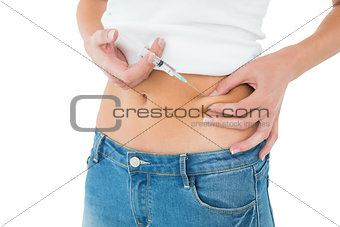 Close-up mid section of a woman injecting her belly
