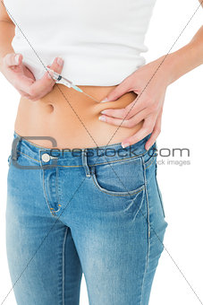 Close-up mid section of a woman injecting her belly