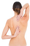 Rear view of a fit topless woman with back pain