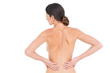 Rear view of a fit topless young woman with back pain