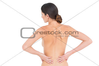 Rear view of a fit topless young woman with back pain