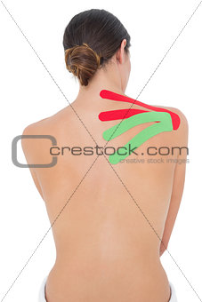 Topless fit woman with red and green strips on shoulder