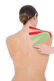 Topless fit woman with red and green strips on shoulder
