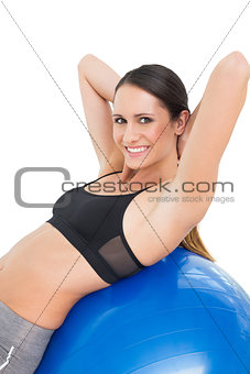 Portrait of a smiling fit woman stretching on fitness ball