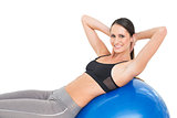 Portrait of a smiling fit woman stretching on fitness ball