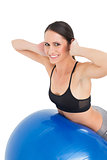 Side view portrait of a fit woman stretching on fitness ball