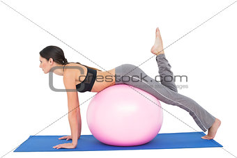 Side view of a fit woman stretching on fitness ball