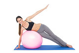 Full length of a fit woman stretching on fitness ball