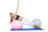 Full length of a fit young woman stretching on fitness ball