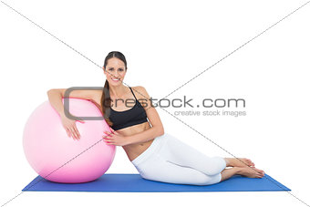 Smiling fit young woman sitting with fitness ball