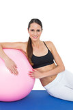 Portrait of a smiling fit woman sitting with fitness ball