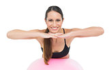 Smiling fit young woman stretching on fitness ball