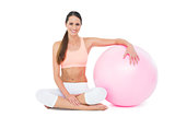 Smiling fit young woman sitting with fitness ball