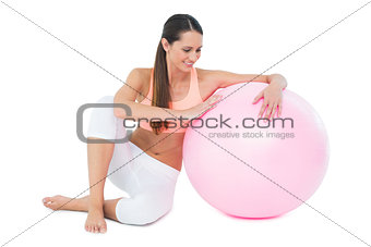 Full length of a fit woman sitting with fitness ball