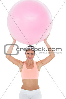 Portrait of a smiling fit woman holding up fitness ball