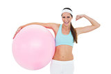 Cheerful fit woman flexing muscles  with fitness ball