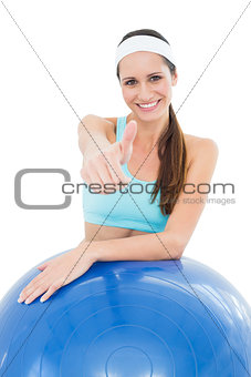 Smiling fit woman with fitness ball gesturing thumbs up