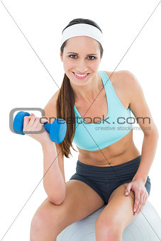 Fit woman exercising with dumbbell on fitness ball