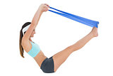 Side view of a fit woman exercising with a blue yoga belt