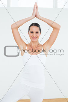 Sporty woman with joined hands over head at a fitness studio