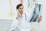 Doctor with spine x-ray picture using the telephone