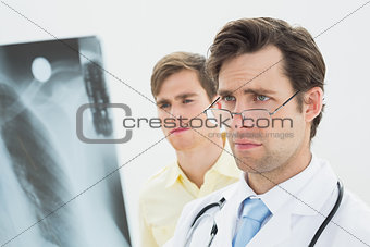Concentrated male doctor and patient examining lungs x-ray